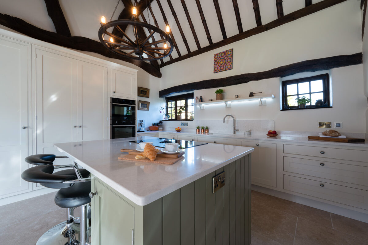 Green shaker kitchen with island seating and wood flooring