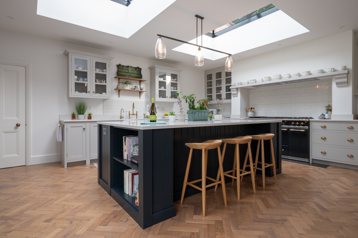 Handmade shaker kitchen by Holme Tree with navy island, light painted cabinetry, oak bar stools, and herringbone wood flooring in a spacious family kitchen.