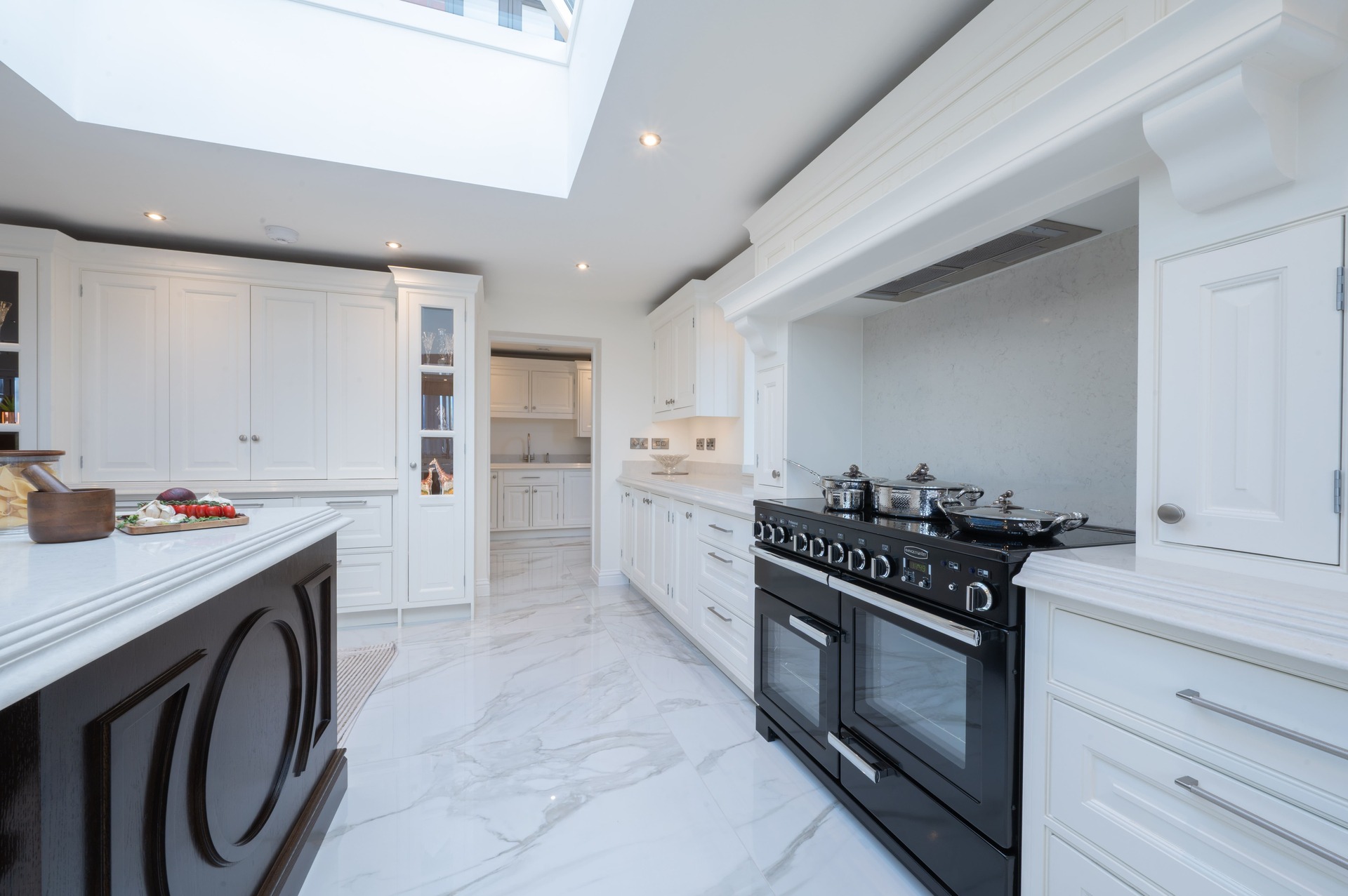 Luxury bespoke white kitchen by Holme Tree featuring traditional in-frame cabinetry, large range cooker alcove, marble-effect flooring, and handcrafted detailing.