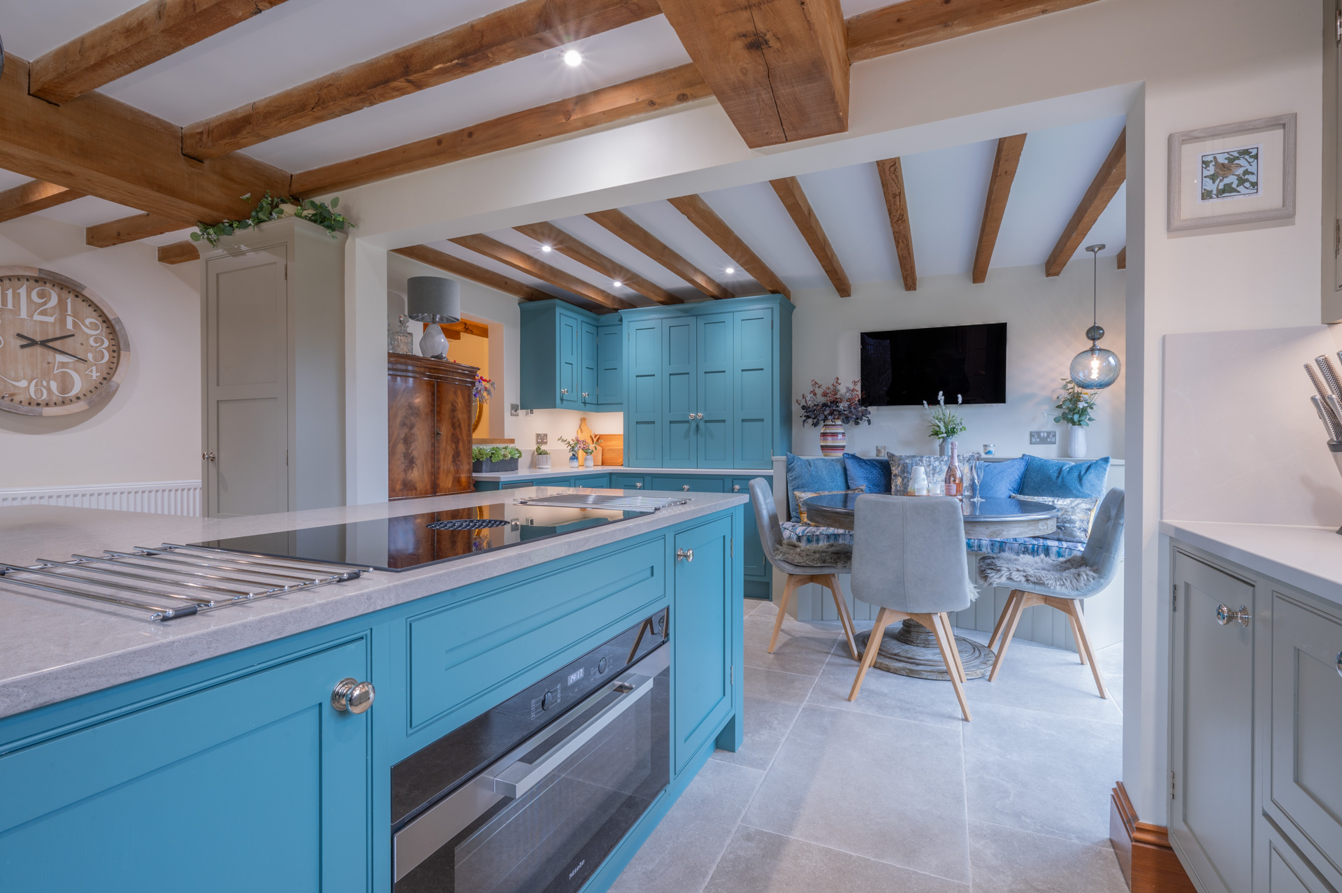 Bespoke blue handmade kitchen by Holme Tree featuring exposed oak beams, painted cabinetry, and open-plan family dining space in a Leicestershire home.
