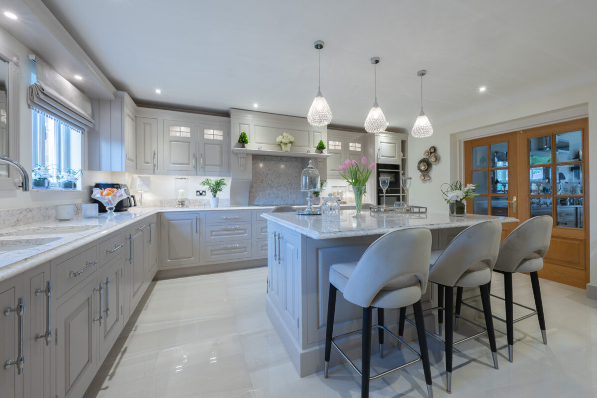 Luxury handmade grey shaker kitchen by Holme Tree with large island, marble-effect worktops, pendant lighting, and bespoke cabinetry in a spacious family home.
