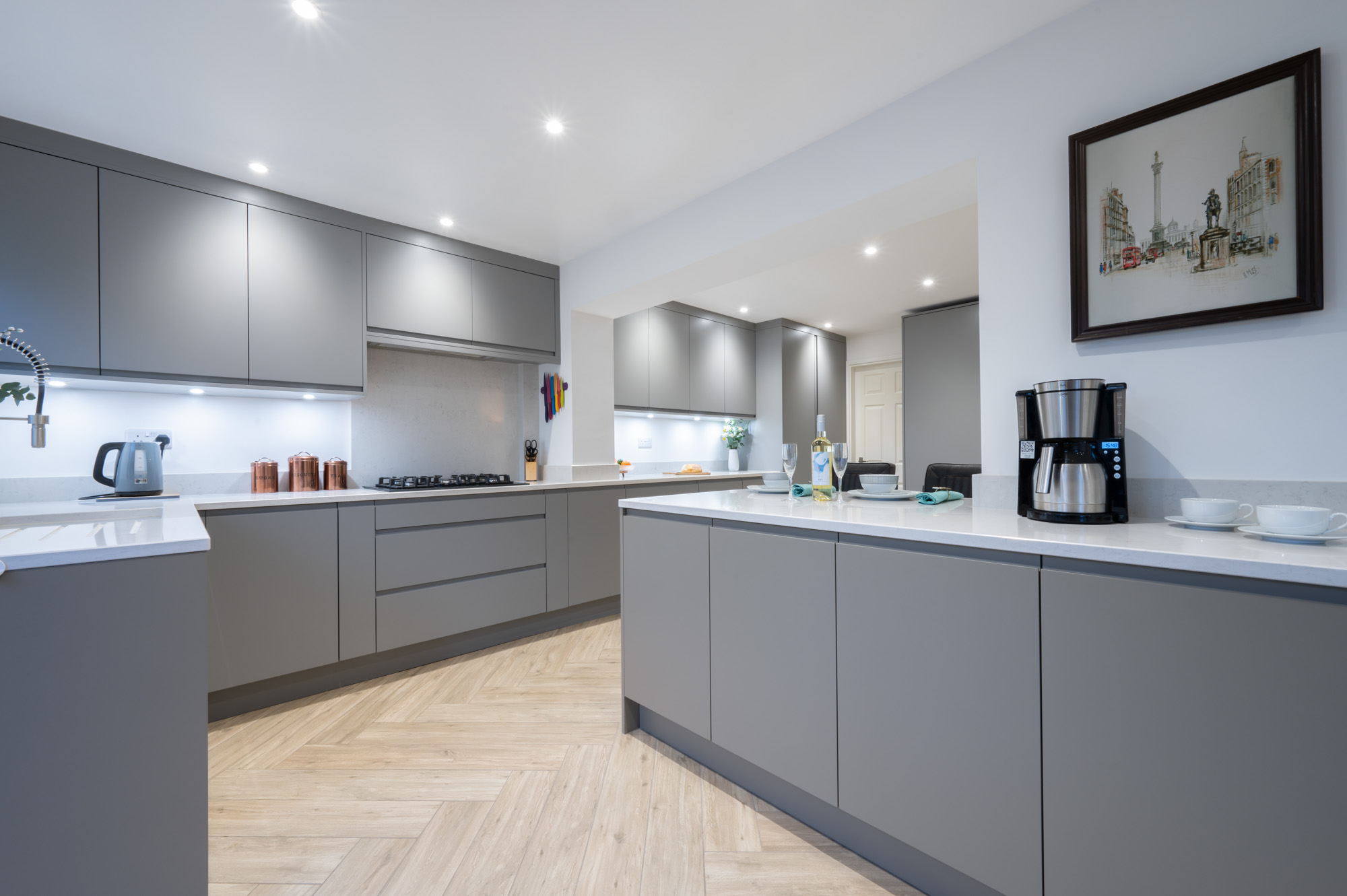 Contemporary grey handleless kitchen with large island, quartz worktops and open-plan layout by Holme Tree Kitchens