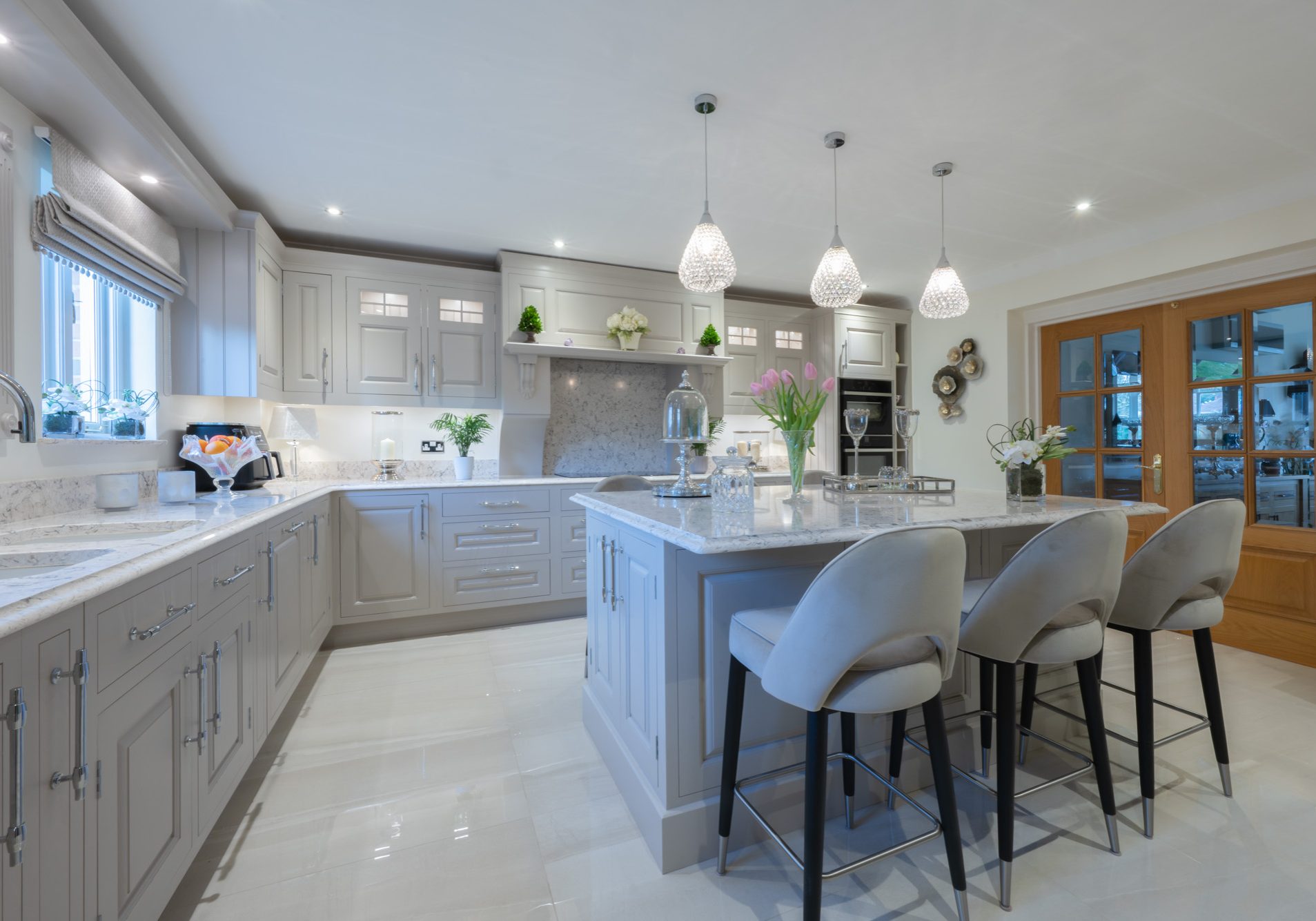 Luxury handmade grey shaker kitchen by Holme Tree with large island, marble-effect worktops, pendant lighting, and bespoke cabinetry in a spacious family home.